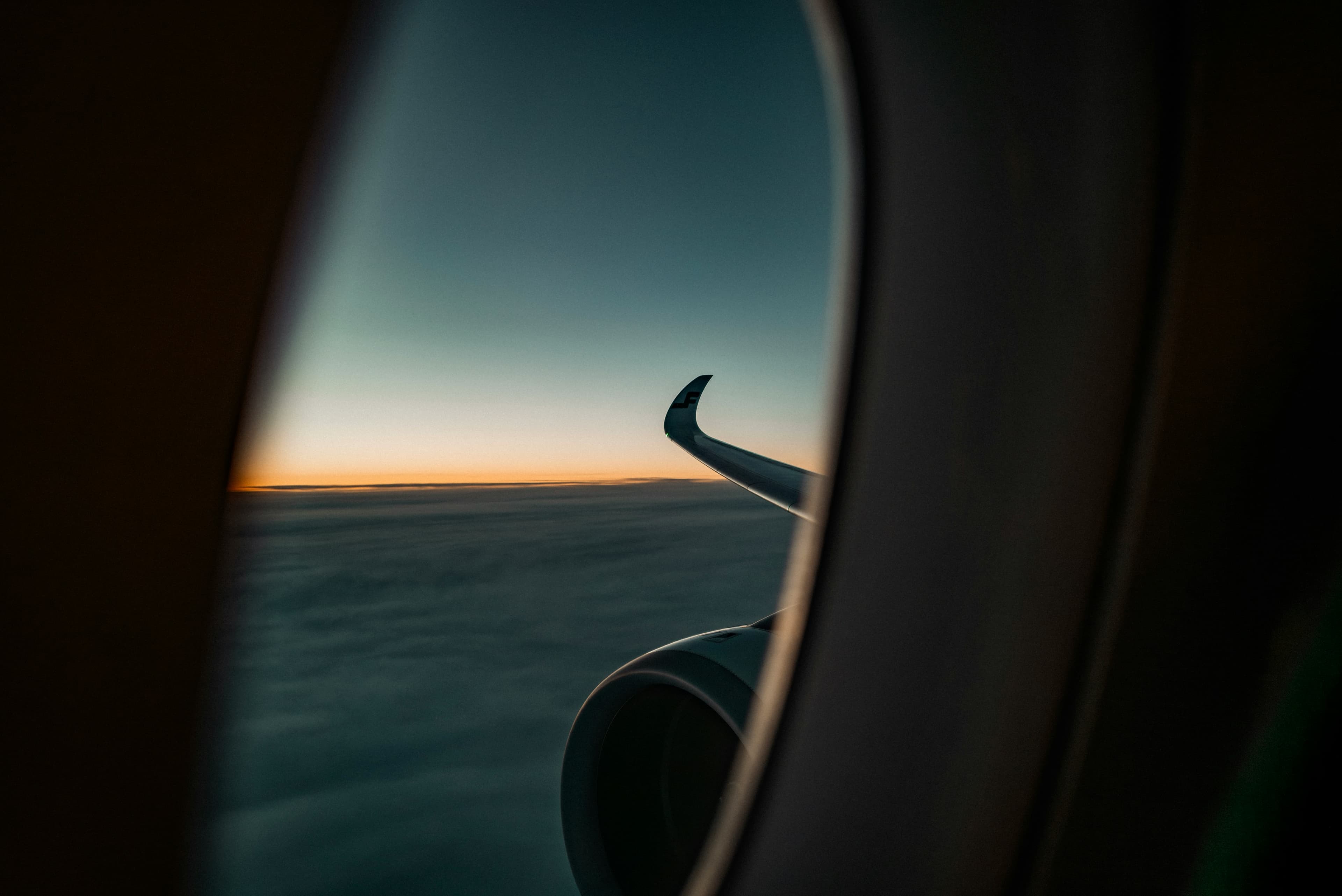 View from an airplane window of the wing and clouds at sunset